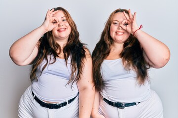 Fototapeta na wymiar Plus size caucasian sisters woman wearing casual white clothes doing ok gesture with hand smiling, eye looking through fingers with happy face.
