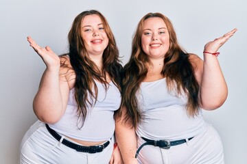 Plus size caucasian sisters woman wearing casual white clothes smiling cheerful presenting and pointing with palm of hand looking at the camera.