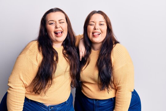 Young plus size twins wearing casual clothes winking looking at the camera with sexy expression, cheerful and happy face.