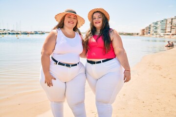 Two plus size overweight sisters twins women happy at the beach on summer holidays