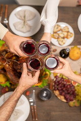 Overview of glasses of red wine held by four members of family during toast