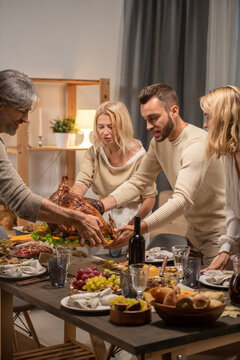 Young and matue men holding tray with homemade roasted turkey over table