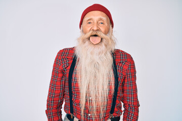 Old senior man with grey hair and long beard wearing hipster look with wool cap sticking tongue out happy with funny expression. emotion concept.