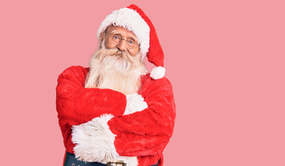 Old senior man with grey hair and long beard wearing traditional santa claus costume happy face smiling with crossed arms looking at the camera. positive person.