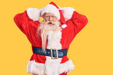 Old senior man with grey hair and long beard wearing traditional santa claus costume crazy and scared with hands on head, afraid and surprised of shock with open mouth