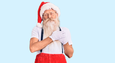 Old senior man with grey hair and long beard wearing santa claus costume with suspenders smiling with hands on chest with closed eyes and grateful gesture on face. health concept.