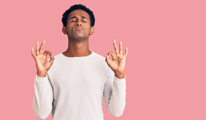 African handsome man wearing casual winter sweater relax and smiling with eyes closed doing meditation gesture with fingers. yoga concept.