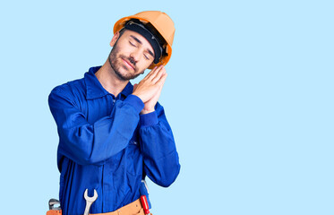 Young hispanic man wearing worker uniform sleeping tired dreaming and posing with hands together while smiling with closed eyes.