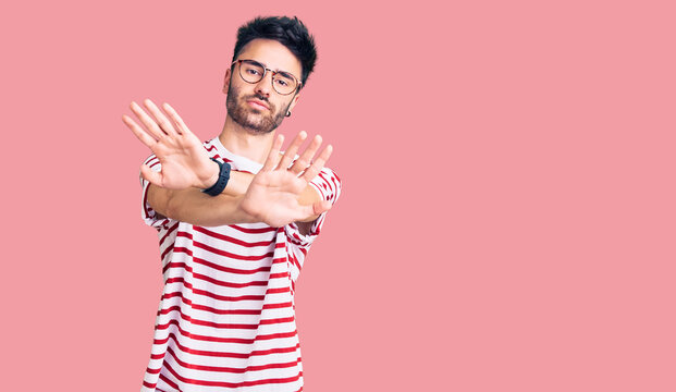 Young hispanic man wearing casual clothes rejection expression crossing arms doing negative sign, angry face