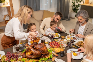 Young careful parents giving drinks to their little son and daughter by dinner