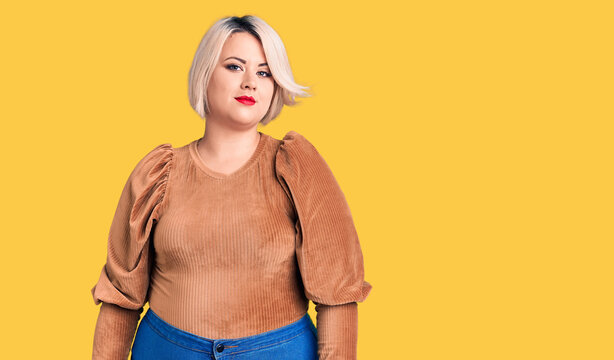 Young blonde plus size woman wearing casual sweater relaxed with serious expression on face. simple and natural looking at the camera.