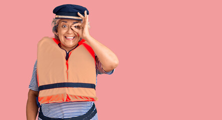 Senior woman with gray hair wearing nautical lifejacket smiling happy doing ok sign with hand on eye looking through fingers