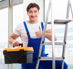 Young repairman climbing ladder at construction site