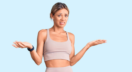 Beautiful caucasian woman wearing sportswear clueless and confused with open arms, no idea concept.