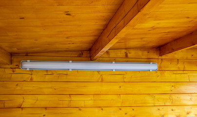 Attaching an LED lamp for a wooden garden house.