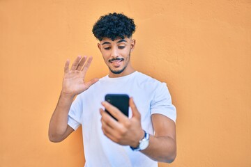 Young arab man smiling happy doing video call using smartphone at city.