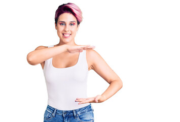 Young beautiful woman with pink hair wearing casual clothes gesturing with hands showing big and large size sign, measure symbol. smiling looking at the camera. measuring concept.