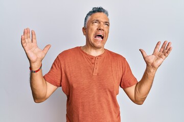 Handsome middle age mature man wearing casual clothes crazy and mad shouting and yelling with aggressive expression and arms raised. frustration concept.