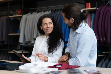 Confident latin female entrepreneur with tablet talking to employee inside clothing store. owner, small business, successful, community concept..