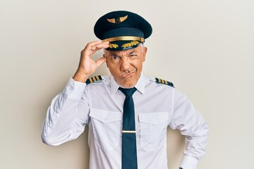 Handsome middle age mature man wearing airplane pilot uniform worried and stressed about a problem with hand on forehead, nervous and anxious for crisis