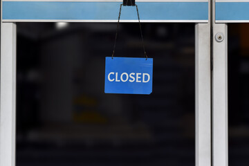 A sign "closed" hanging on the glass door in a shop, Close due to financial difficulties and economic crisis.