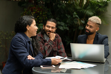 Group of latin business colleagues with laptop collaborating and discussing project plans outside the office. Connection, workplace, networking, concept..
