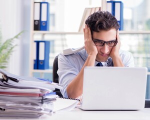 Young businessman under pressure in office to deliver tasks