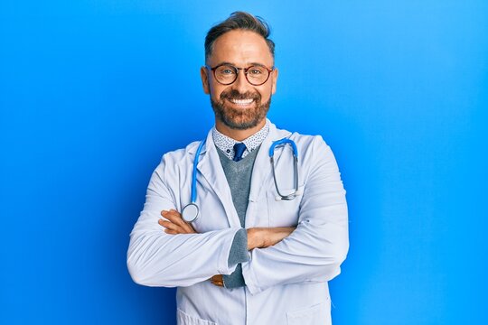 Handsome middle age man wearing doctor uniform and stethoscope happy face smiling with crossed arms looking at the camera. positive person.