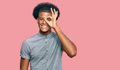 African american man with afro hair wearing casual clothes doing ok gesture with hand smiling, eye looking through fingers with happy face.