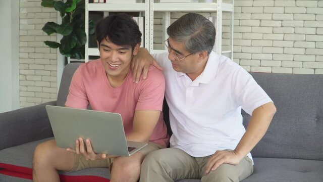 Senior father and growing son are talking and watching laptop computer