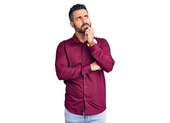Young hispanic man wearing casual clothes serious face thinking about question with hand on chin,...