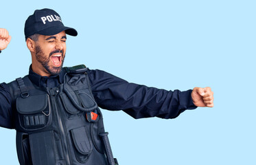 Fototapeta premium Young hispanic man wearing police uniform dancing happy and cheerful, smiling moving casual and confident listening to music