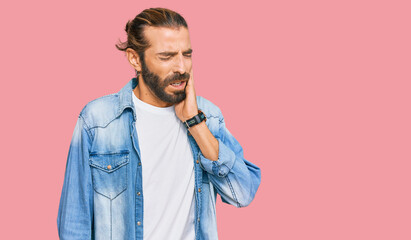 Attractive man with long hair and beard wearing casual denim jacket touching mouth with hand with painful expression because of toothache or dental illness on teeth. dentist