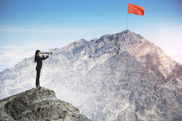Obraz premium Businesswoman standing on mountain top and looking into the distance