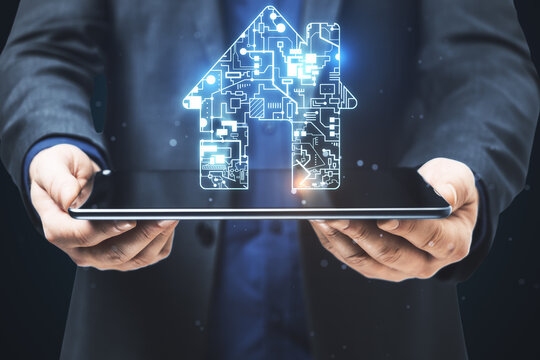 Businessman holding digital tablet with circuit house hologram. - Powered by Adobe