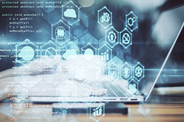 Hand using laptop with business analytics diagram and programming backdrop.