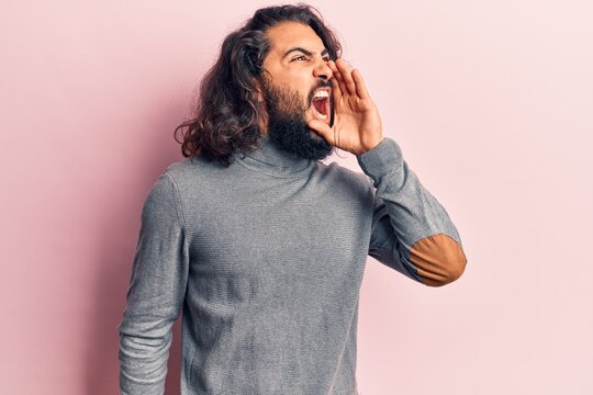 Young arab man wearing casual clothes shouting and screaming loud to side with hand on mouth. communication concept.