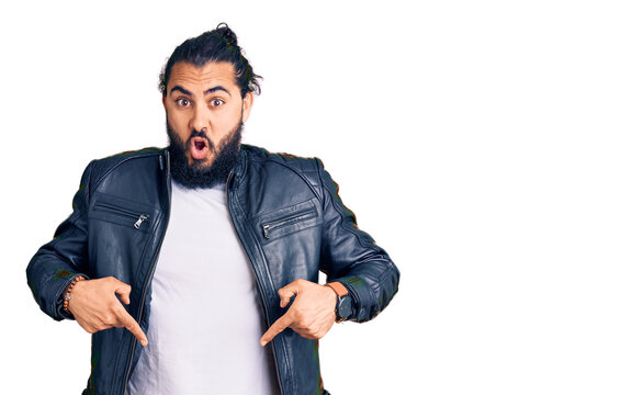 Young arab man wearing casual leather jacket pointing down with fingers showing advertisement, surprised face and open mouth