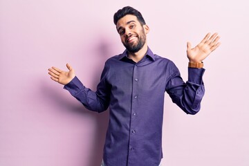 Young handsome man with beard wearing casual shirt clueless and confused expression with arms and...