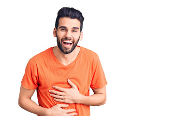 Fototapeta premium Young handsome man with beard wearing casual t-shirt smiling and laughing hard out loud because funny crazy joke with hands on body.