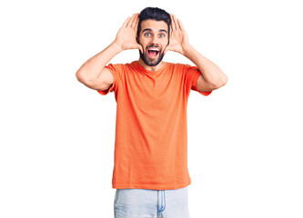 Fototapeta premium Young handsome man with beard wearing casual t-shirt smiling cheerful playing peek a boo with hands showing face. surprised and exited