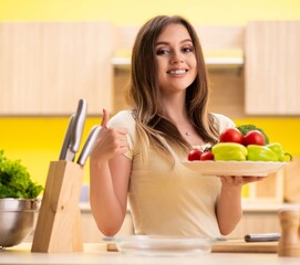 Obraz na płótnie Canvas Young woman preparing salad at home in kitchen