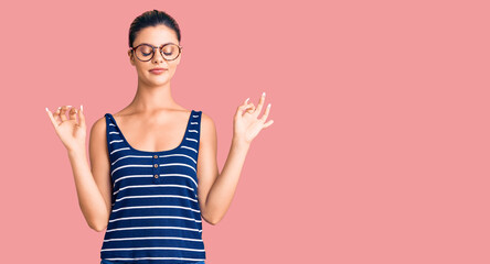 Young beautiful woman wearing casual clothes and glasses relax and smiling with eyes closed doing meditation gesture with fingers. yoga concept.