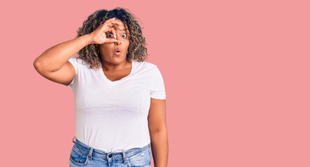 Young african american plus size woman wearing casual clothes doing ok gesture shocked with surprised face, eye looking through fingers. unbelieving expression.