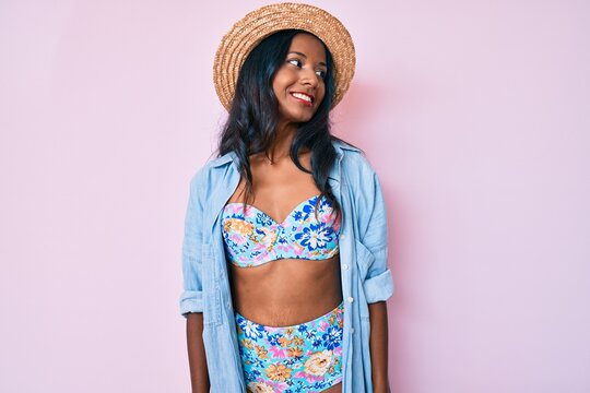 Young indian girl wearing bikini and summer hat looking to side, relax profile pose with natural face and confident smile.