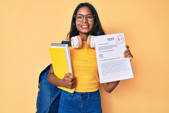 Young indian girl wearing backpack showing a passed exam smiling with a happy and cool smile on face. showing teeth.