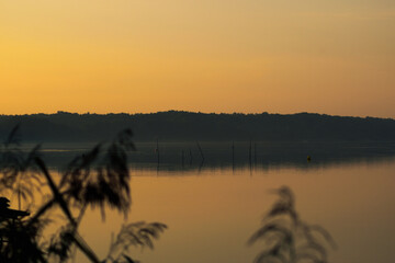 Great colorful sunrise on a calm lake with reeds on the shore