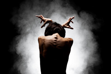 half silhouette modern ballet dancer posing on dark background with smoke