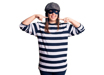 Young beautiful brunette woman wearing burglar mask smiling cheerful showing and pointing with fingers teeth and mouth. dental health concept.