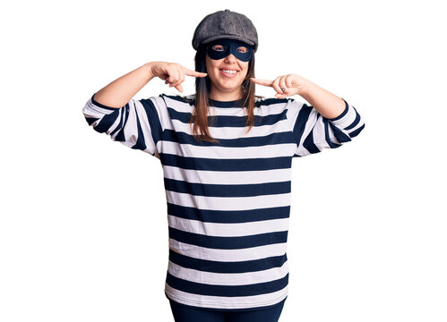Young beautiful brunette woman wearing burglar mask smiling cheerful showing and pointing with fingers teeth and mouth. dental health concept.